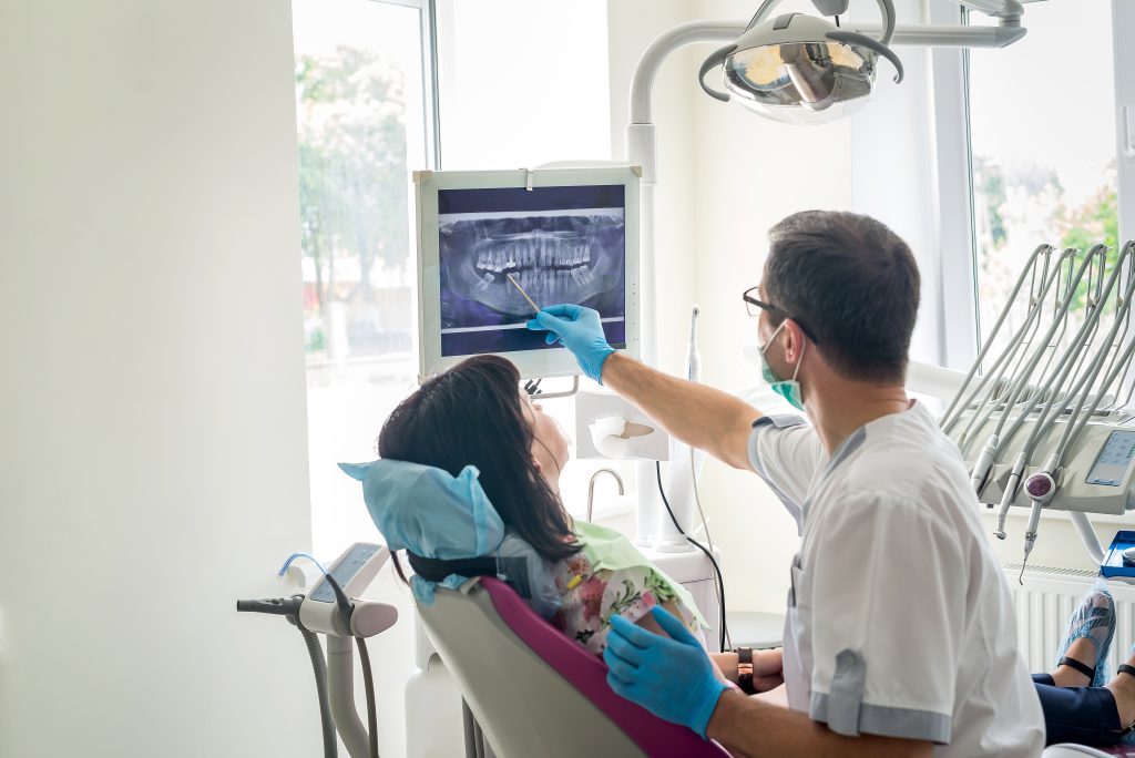 Doctor dentist showing patient's teeth on X ray